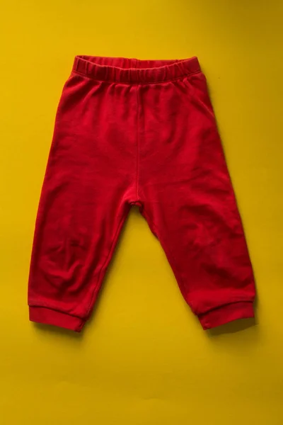 Красные детские спортивные штаны на желтом фоне . — стоковое фото