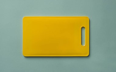 Sarı plastik kesme tahtası mavi arka plan üzerinde renkli, sayfa görünümü.