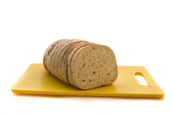 Pão de grão integral cozido no forno fresco e pão fatiado em placa de corte de plástico isolado em um fundo branco . — Fotografia de Stock