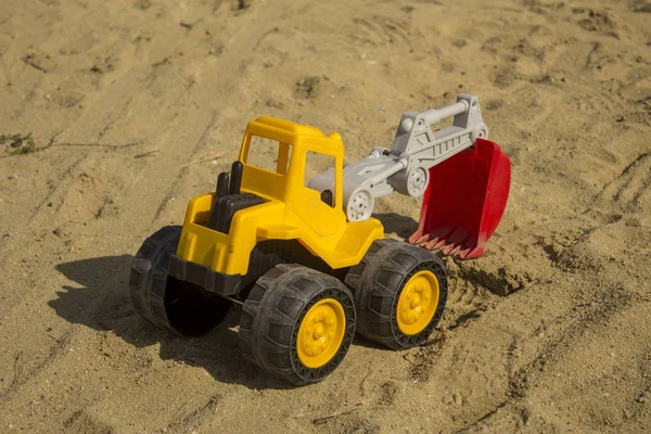 Żółta koparka zabawka w piasku na plaży. Koncepcja zabawki chłopca. — Zdjęcie stockowe