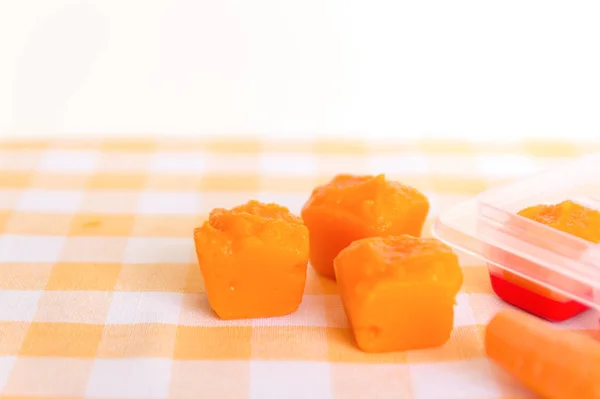 Готовлю детское питание, домашнее. Замороженная морковь, сделанная как кубик льда на жёлтой доске. Концепция здорового питания детей. Селективный фокус . — стоковое фото