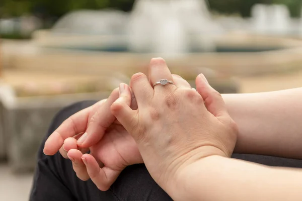 Una mujer joven con artritis reumatoide descansa sentada en un banco en un patio de un hospital. Las manos y las piernas están deformadas. Siente dolor. Enfoque seleccionado . — Foto de Stock