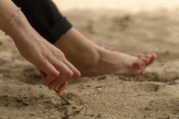 Mladá žena, která má revmatoidní artritidu, si na písku u pláže odpočne. Ruce a nohy jsou deformované. Cítí bolest. Vybrané zaměření. — Stock fotografie