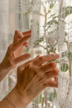 Young woman having rheumatoid arthritis trying to move the curtains. Hands and legs are deformed. She feels pain. Selective focus. clipart