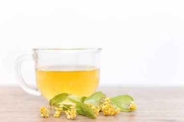 Kurumuş ıhlamur suyuyla ahşap bir masada bir bardak çay. Ihlamur üzerine seçili odak.