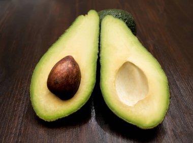 Yeşil avokado bir kemik ile ahşap bir masa üzerinde ikiye böldüm