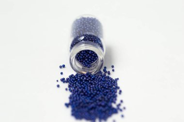 Cam kavanozlarda çok renkli boncuklar. Boncuklar beyaz bir ba üzerine dökülür