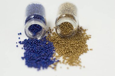 Cam kavanozlarda çok renkli boncuklar. Boncuklar beyaz bir ba üzerine dökülür