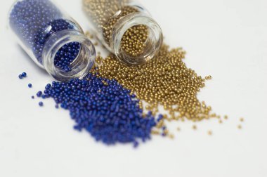 Cam kavanozlarda çok renkli boncuklar. Boncuklar beyaz bir ba üzerine dökülür