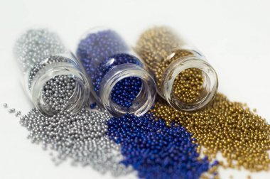 Cam kavanozlarda çok renkli boncuklar. Boncuklar beyaz bir ba üzerine dökülür