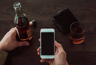 Bir adam elinde bir cep telefonu tutar. Masada sonraki bir 