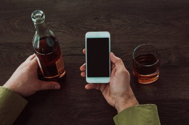 Bir adam elinde bir cep telefonu tutar. Masada sonraki bir 