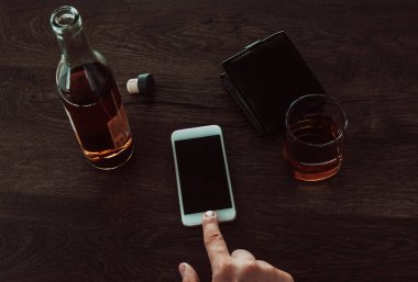 Bir adam cep telefonuna parmağını basıyor. Masada sonraki bir