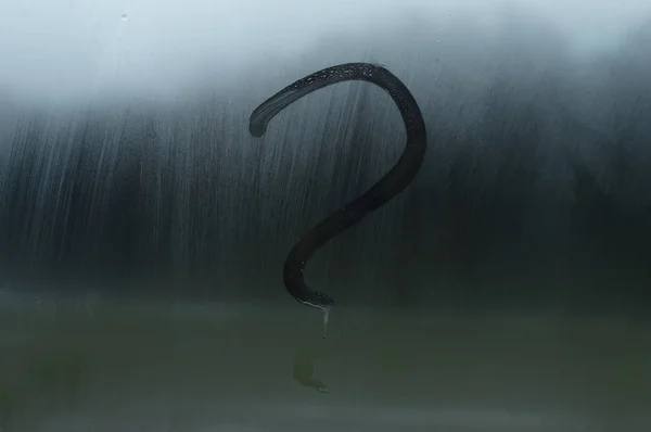 A question mark is drawn with a finger on a misted window. The q