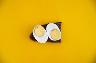 Çavdar ekmeği ve haşlanmış yumurta bir sandviç sarı bir backgrou yatıyor