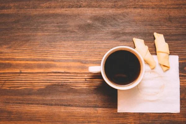 Taza de café en una servilleta blanca con galletas en un fondo de madera —  Fotos de Stock