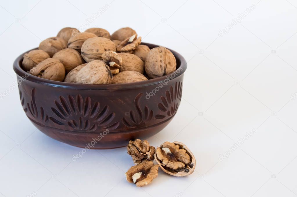 walnuts lie in a bowl, chopped nuts nearby, on a white backgroun