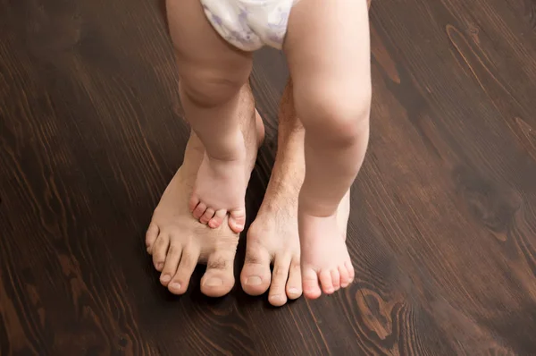 Ребенок делает первый шаг. Большие мужские ноги с маленьким ребенком — стоковое фото