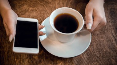kız bir kafede oturur ve onu ha bir fincan çay ve bir telefon tutar