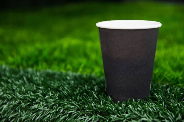 Taza de papel con costo de café en hierba verde —  Fotos de Stock