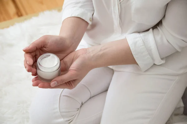 Girl in white smears hand cream. Hand care. Smear cream.