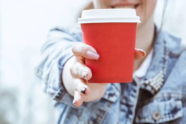 Una chica sostiene una taza de café de papel rojo. Un vaso de café en primer plano —  Fotos de Stock