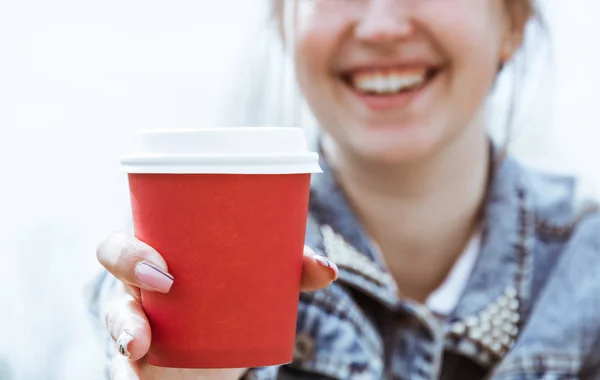 Una chica sostiene una taza de café de papel rojo. Un vaso de café en primer plano —  Fotos de Stock