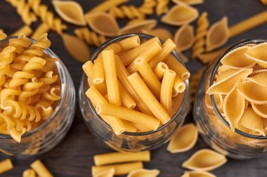 Tahta bir masada çiğ makarna. Yukarıdan manzara. Spagetti, lazanya, fusilli, besbarmak erişte.