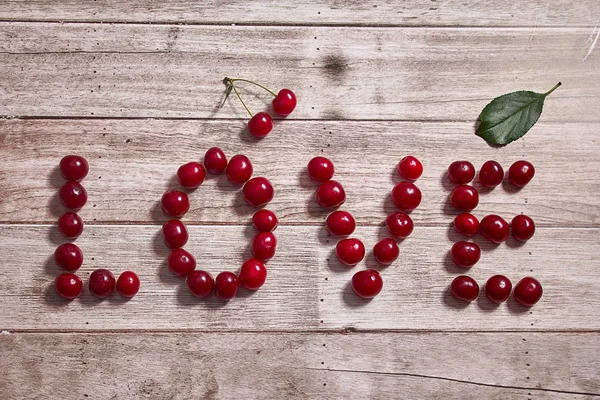 The word love of cherry on a wooden background.