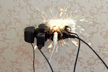 Aşırı yüklenmiş soket, kıvılcım. Elektrik şoku tehlikesi, yangın. Kablo, fiş, ateş.