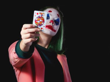 Karanlık bir arka planda Joker kostümlü cadılar bayramı kızı için bir palyaço resmi, stüdyoda fotoğraf çekimi..