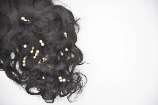 Dark brown curly hair with pearls on the white background