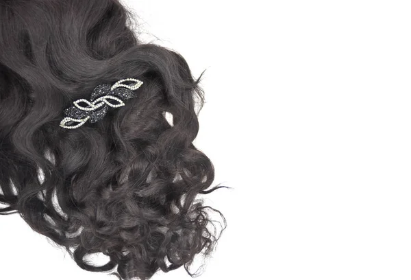 Dark brown curly hair with crystal hair-slide on the white background