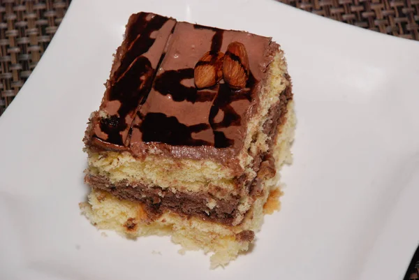 Beyaz plaka üzerinde çikolata ve badem ile pasta kare parçası