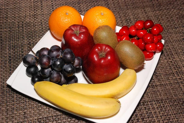 Fresh Oranges Apples Grapes Kiwis Cherries Bananas White Plate Brown — Stock Photo, Image