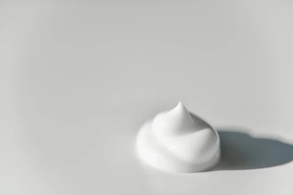 Porção de creme branco no fundo branco com a luz lateral — Fotografia de Stock