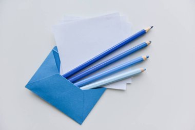 Seçici odak, dört mavi kalem ve mavi zarfın içinden beyaz kağıtlar.