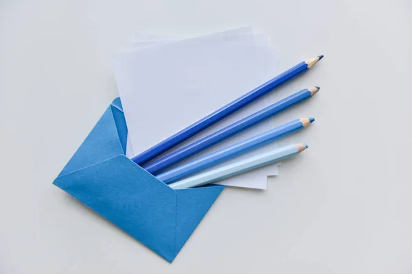 有选择的焦点 四支蓝色铅笔 蓝色信封里的白纸 图库图片