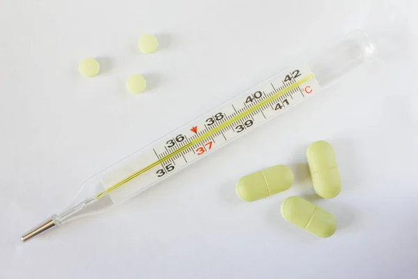 Thermometer and pills on a light background — Stock Photo, Image