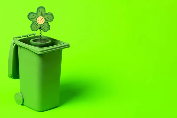 Green trash can with flowers on a green background