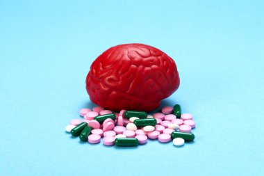 Pembe haplarla mavi arka planda kırmızı beyin. Beyin için bazı haplar. Bu ilaçlar, psikofarmasötikler, nootropics ve diğer ilaçlar için sembolik. İlaç. Beyin tedavisi