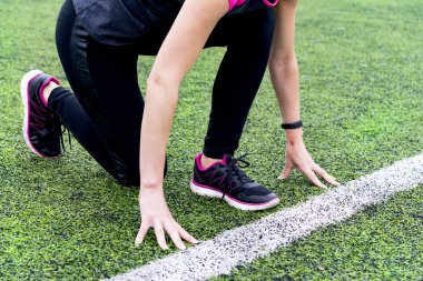 Siyah tozluk ve pembe bir blazer bir kız bir açık hava arenada bir koşu bandı üzerinde çalıştırmak için hazırlanan ve bir koşucu poz duruyor