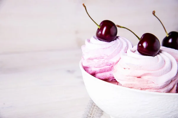 在木制背景的白色盘子中，有很多甜的粉红色樱桃蛋糕。粉红色樱桃棉花糖. — 图库照片