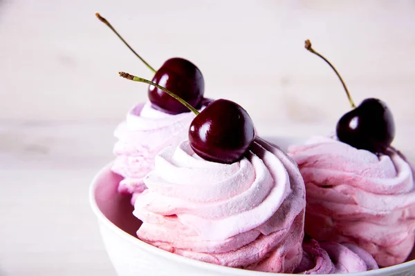 Dużo słodkich różowych ciastek wiśniowych w białej płytce na drewnianym tle. Marshmallows z różowej wiśni. — Zdjęcie stockowe