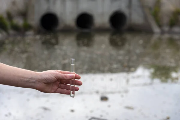 Comprobación de la calidad del agua en aguas residuales. Tubo de ensayo con una muestra en la mano. Tratamiento de aguas residuales —  Fotos de Stock
