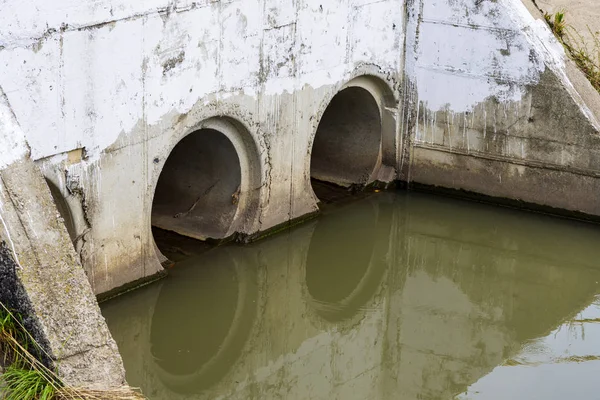 Una tubería de drenaje o alcantarillado o alcantarillado vierte aguas residuales en un río. Aguas residuales o domésticas o municipales que son producto de una comunidad de personas — Foto de Stock