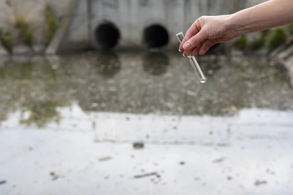 Controle van de kwaliteit van het water in de afvalwaterzuivering. Reageerbuis met een monster in de hand. Afvalwaterzuivering — Stockfoto