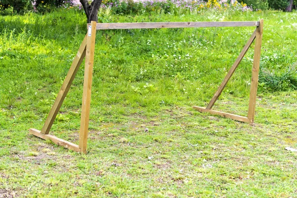 wooden football goal without a net on a green field. Make a football goal for children in the courtyard of the house