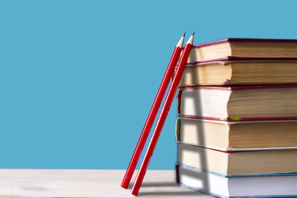 En bunt med böcker och två röda blyertspennor på en blå bakgrund, trappor, klätter böcker, få kunskap, tillbaka till skolans koncept — Stockfoto