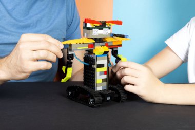 Lego robot bir çocuk ve bir adam plastik parçalardan bir robot monte, tren. En ateşli aletler. E-öğrenme. Modern eğitim teknolojileri. Eğitim